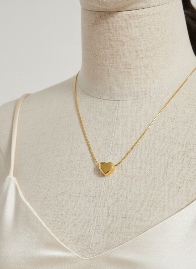 Gold heart-shaped pendant necklace on a mannequin with a plain background