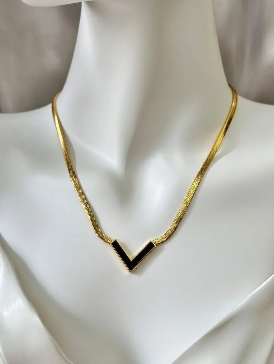 Gold necklace with a black pendant on a mannequin
