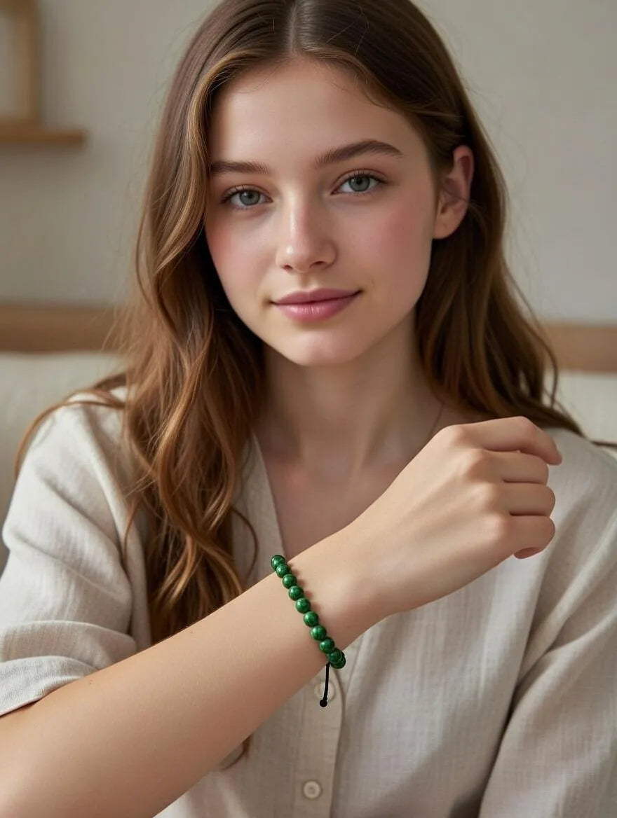 Unisex adjustable bracelet featuring polished green jasper beads with black marbled patterns, displayed on a white surface with elegant neutral fabric draping.