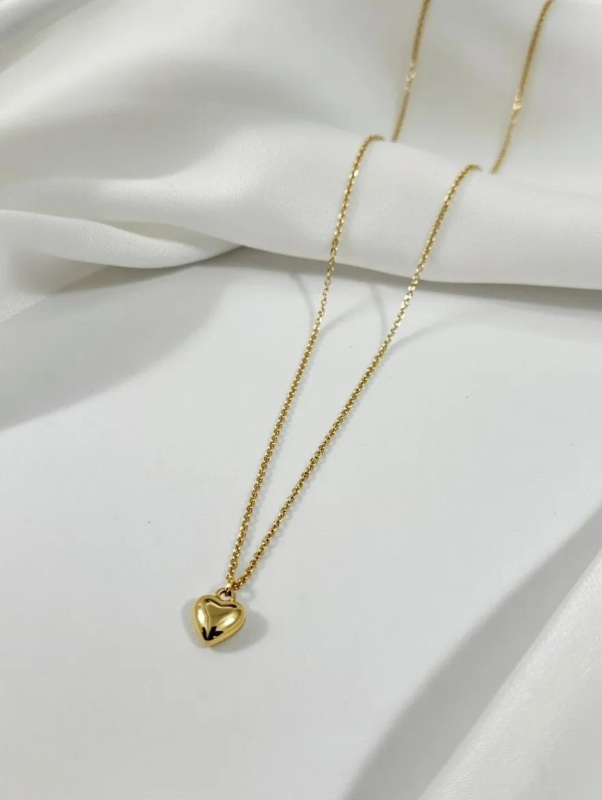 A delicate gold-toned link chain necklace featuring a small polished heart pendant